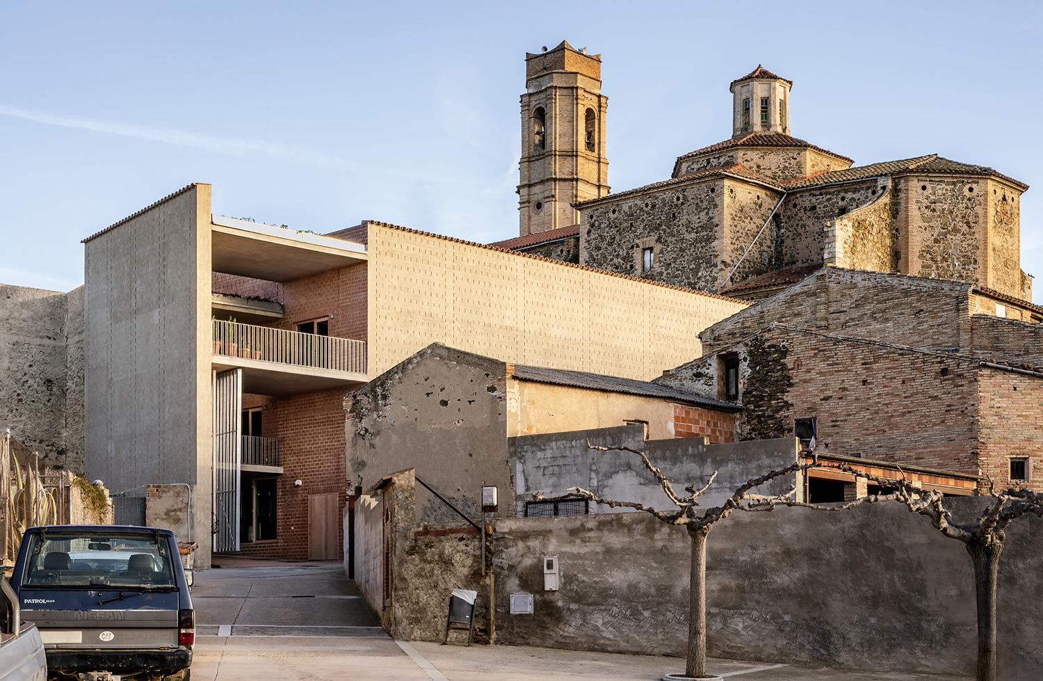 Die Clos Pachem Winery – ein großes, neues Backsteingebäude neben einem älteren Bestand im spanischen Gratallops bei Barcelona vor einem blauen Himmel.